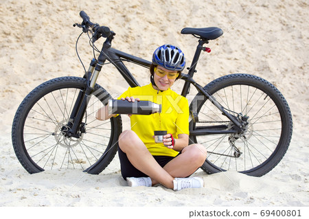 girl cyclist pours tea from a thermos on the background of a Bic 69400801