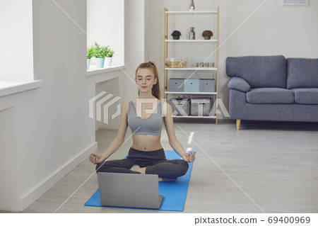 Young girl sitting and meditating during online yoga class at home Young girl sitting and meditating during online yoga class at home 69400969