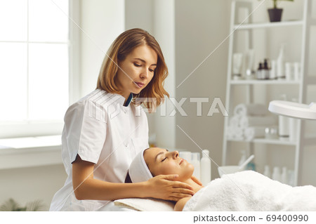 Woman cosmetologist making face massage for woman client in beauty spa salon Woman cosmetologist making face massage for woman client in beauty spa salon 69400990