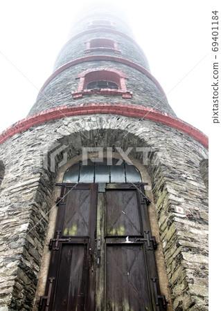 A lookout tower in the clouds. The stone tower is surrounded by a white mist. 69401184