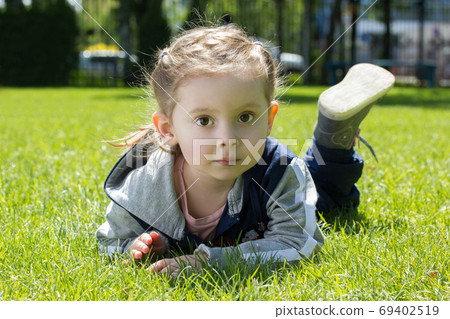 Three years old girl portrait on a grass in outdoor park 69402519