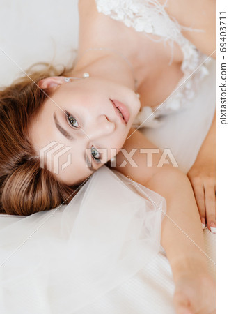 view top. bride in white dress lying in bed. 69403711