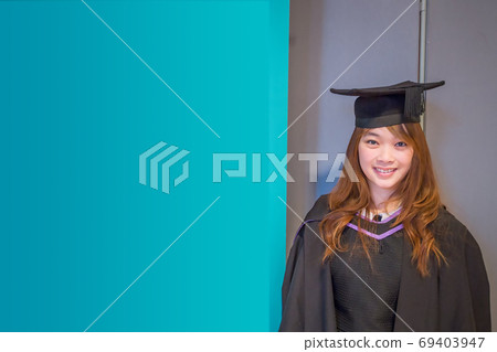 Graduation day, portrait of smiling girl student in a graduation cap and gown. Postcard / Poster 69403947