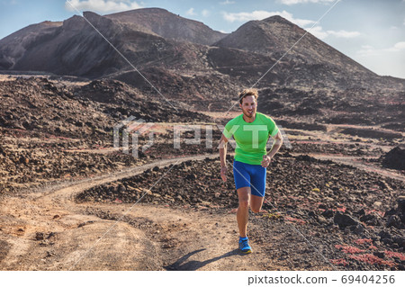 Runner man athlete running on trail run outdoor mountains landscape. Difficult endurance training ultra running marathon race in sun 69404256