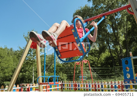 Girl child riding on swing, sunny summer day 69405711