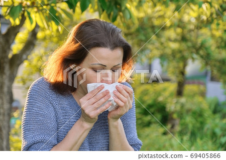 Mature woman sneezing in handkerchief, allergy to pollen, colds Mature woman sneezing in handkerchief, allergy to pollen, colds 69405866