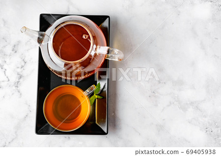 Top view of glass tea cup and glass kettle on black tray and white backround 69405938