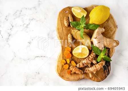 Top view of a wooden board with ginger, turmeric roots, lemon and mint Top view of a wooden board with ginger, turmeric roots, lemon and mint 69405943