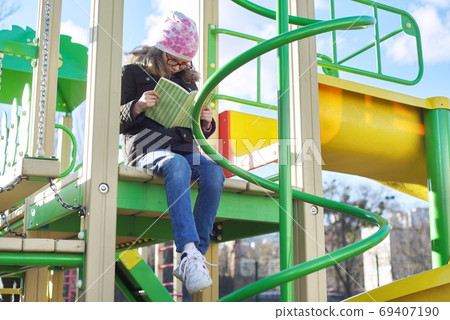 Smart child girl, 8-9 years old, in jacket hat glasses, reading book 69407190
