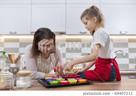 Mothers day, mother and daughter child 9, 10 years old preparing cupcakes 69407211