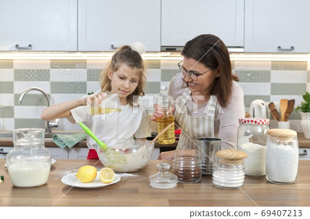Mother and daughter child together at home kitchen preparing cookies Mother and daughter child together at home kitchen preparing cookies 69407213