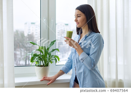 Young beautiful woman with drink green blended smoothie kiwi Young beautiful woman with drink green blended smoothie kiwi 69407564