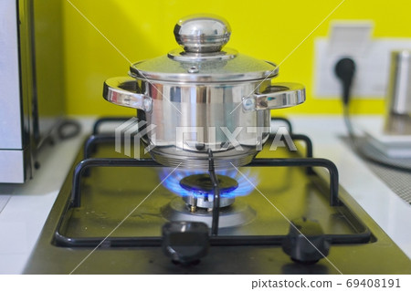 Metal pan with boiling food on a gas burner 69408191