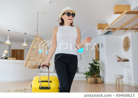 Mature beautiful woman with suitcase in lobby of modern spa resort hotel Mature beautiful woman with suitcase in lobby of modern spa resort hotel 69408623