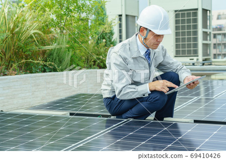 Male worker inspecting solar panels 69410426