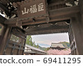 View of the mountain gate surrounded by colorful cherry blossoms from the main gate at the entrance of the historic Kenchoji Temple 69411295