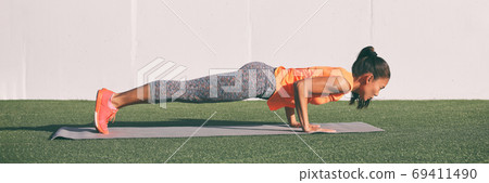 Yoga fitness woman practicing chaturanga pose push ups press up on exercise mat at outdoor home. Fit and healthy young girl doing morning core body workout pushup strength training. Banner panorama. 69411490