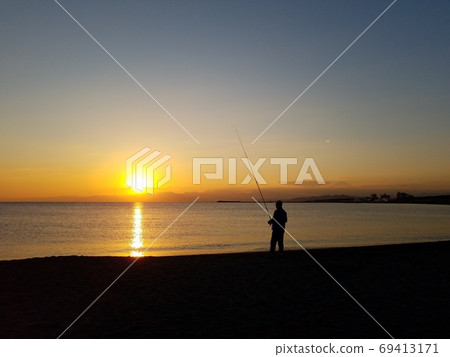 在小春天氣中，一個人在神奈川縣湘南茅崎海岸的夕陽下沐浴時，獨自在一個寧靜的海灘上釣魚[11月] 69413171