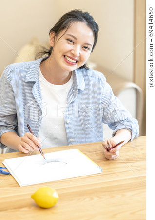一個年輕的女人，她在家裡素描愛好 69414650