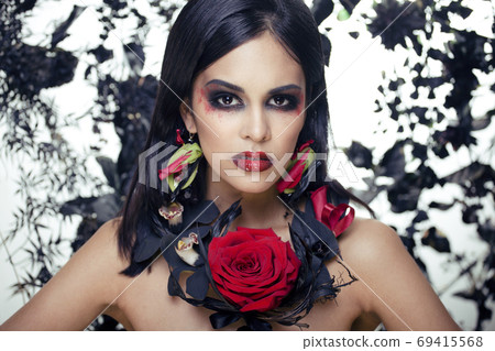 pretty brunette woman with rose jewelry, black and red, bright make up kike a vampire closeup red lips 69415568