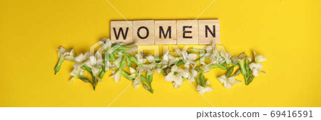 Top view word women spelled in wooden blocks on yellow background with flowers beneath them. Love, 8 march background. Gift, greeting, compliment concept. Copy space. place for text. Top view word women spelled in wooden blocks on yellow background with flowers beneath them. Love, 8 march background. Gift, greeting, compliment concept. Copy space. place for text. 69416591
