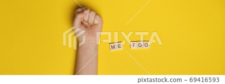 MeToo on wooden alphabet, used for concept of sexual harrassment. Woman fist as protest in shot 69416593