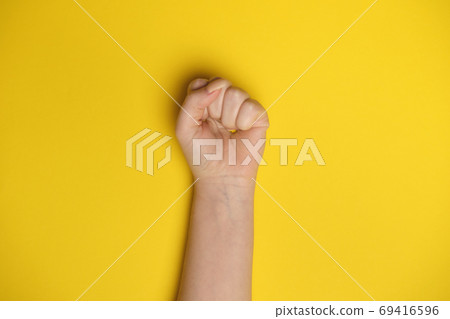 Woman fist as symbol of protest shot on yellow bee background. Woman rights equality concept 69416596