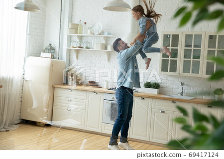 Happy young man lifting in air small preschool child daughter. Happy young man lifting in air small preschool child daughter. 69417124