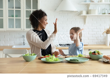 Happy african ethnicity mother giving high five to adopted daughter. Happy african ethnicity mother giving high five to adopted daughter. 69417349