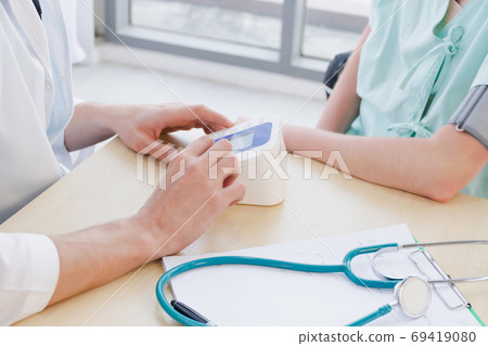 A doctor is examining the heartbeat of the patient 69419080