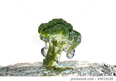 Green broccoli falling in water with splash on white with air bubbles Green broccoli falling in water with splash on white with air bubbles 69419280