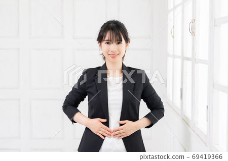 一個年輕的商業女人把她的手放在她的肚子上 一個年輕的商業女人把她的手放在她的肚子上 69419366