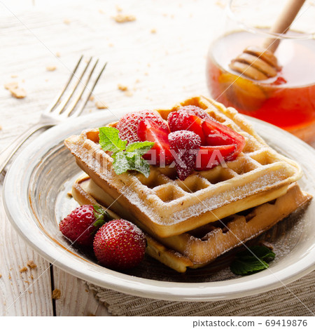 Belgian waffles served with strawberries and mint leaf dusted wi Belgian waffles served with strawberries and mint leaf dusted wi 69419876