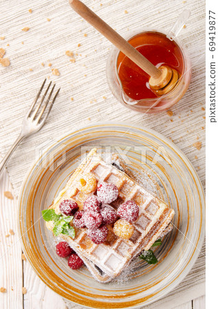 Flat lay view at Belgian waffles served with raspberries and min Flat lay view at Belgian waffles served with raspberries and min 69419877