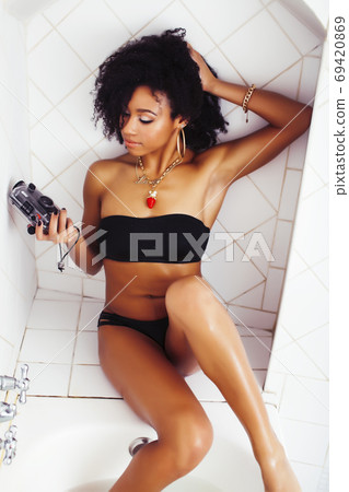 young afro-american teen girl laying in bath with foam, wearing swag jewelry flawless, making selfie young afro-american teen girl laying in bath with foam, wearing swag jewelry flawless, making selfie 69420869