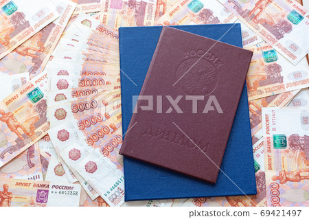 Against the background of five-thousandth bills are two diplomas with honors and a blue 69421497