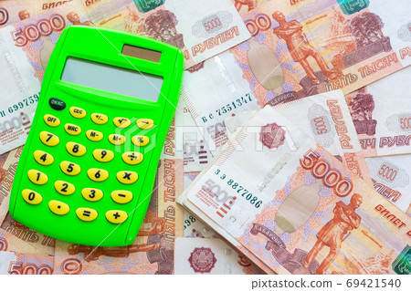 Green calculator and a bunch of five thousandth bills 69421540