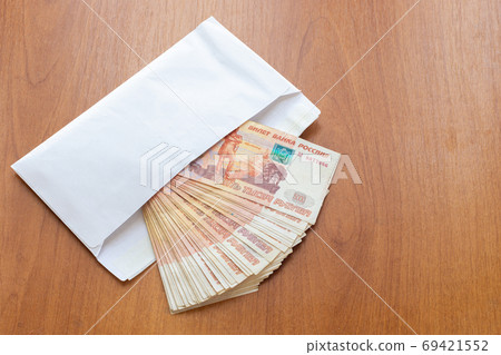 There is a bundle of money in an envelope on the table 69421552