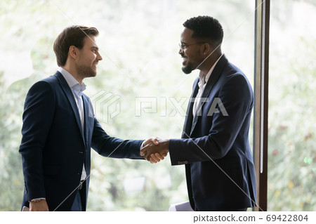 Smiling diverse businessmen handshake closing deal in office 69422804