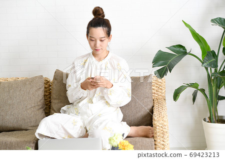 A young woman operating a smartphone on the sofa 69423213