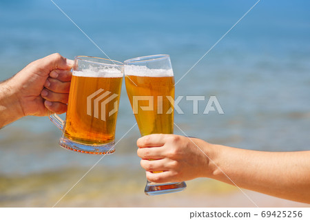 closeup hands holding glasses of beer closeup hands holding glasses of beer 69425256