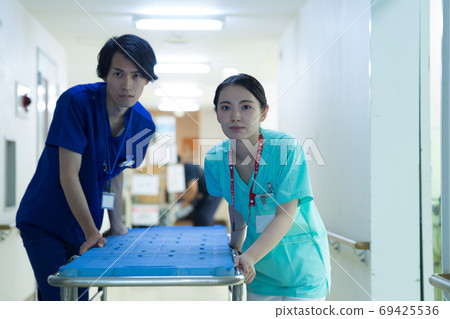Healthcare worker carrying a stretcher 69425536