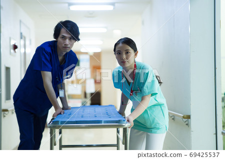 Healthcare worker carrying a stretcher 69425537