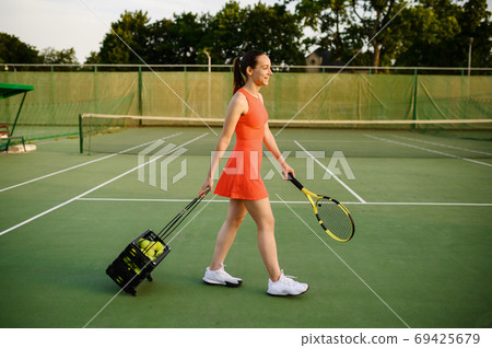 Female tennis player carries basket with balls 69425679