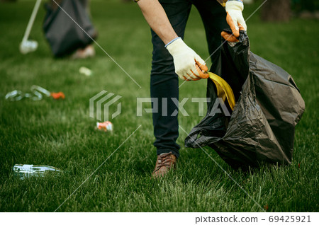 Young man collects garbage in a bag, volunteering 69425921