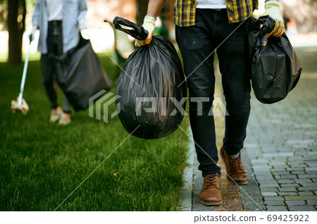 Man holds plastic trash bags in park, volunteering 69425922
