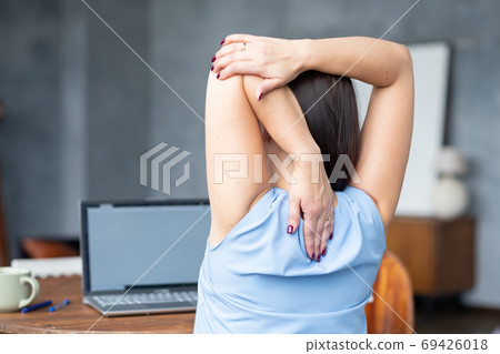 woman stretches her body after hard worling day. Rear view woman stretches her body after hard worling day. Rear view 69426018