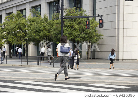 Back view of a businessman running and crossing a pedestrian crossing 69426390