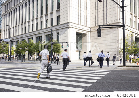 Back view of a businessman running and crossing a pedestrian crossing 69426391
