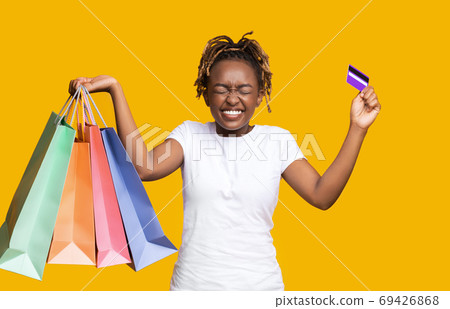 Emotional african woman with purchases and credit card Emotional african woman with purchases and credit card 69426868